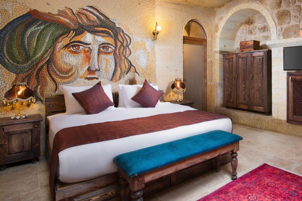 a bedroom with a large bed with a painting on the wall at Cappadocia Pema Cave Hotel in Ortahisar
