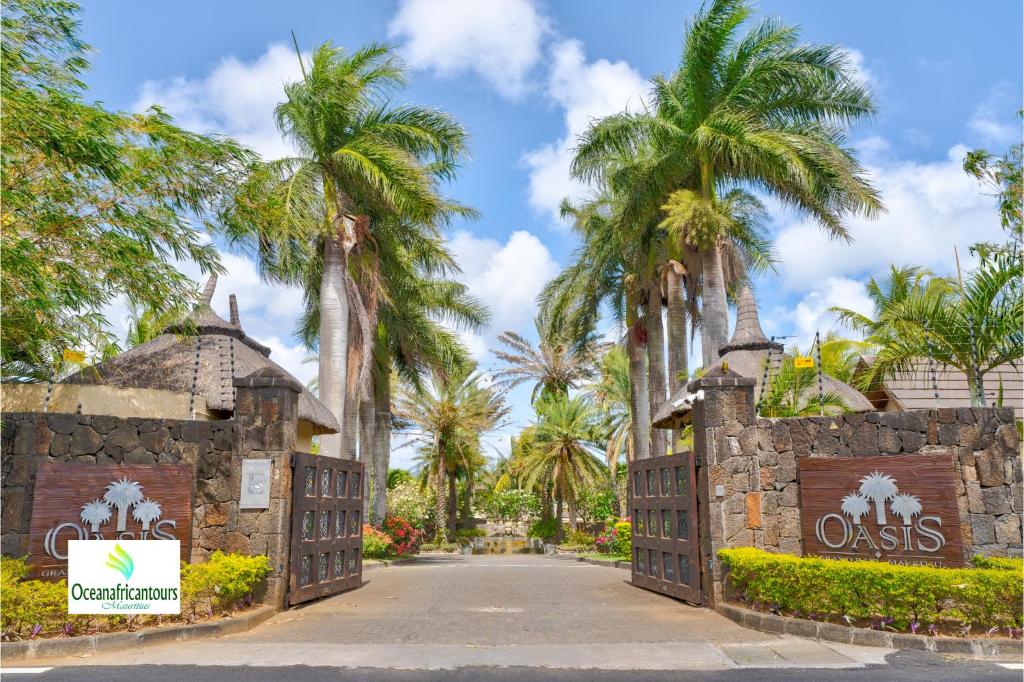 a gate at the entrance to a resort with palm trees at Oasis 1 Villa Tropicale in Grand-Baie