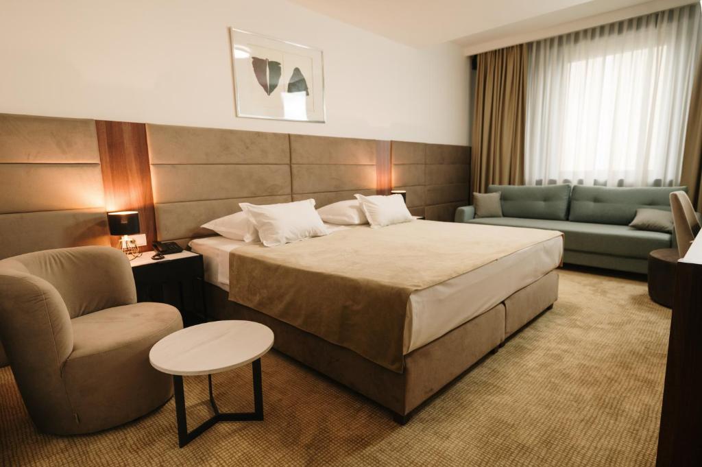 Hotel Slavija Lux في بلغراد: غرفة في الفندق بسرير وكرسي وأريكة