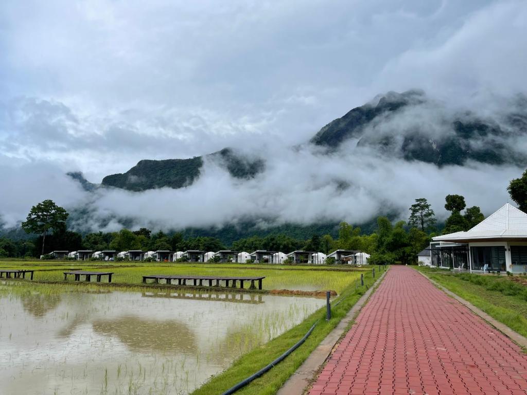 a flooded street with benches in front of a mountain at Family Land Camping Resort in Vang Vieng