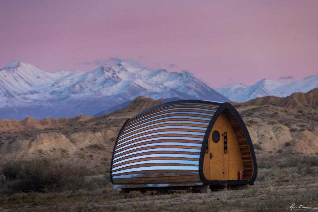 une maison en dôme au milieu d'un désert avec des montagnes dans l'établissement Remote. Forgotten Rivers, à Ak-Say