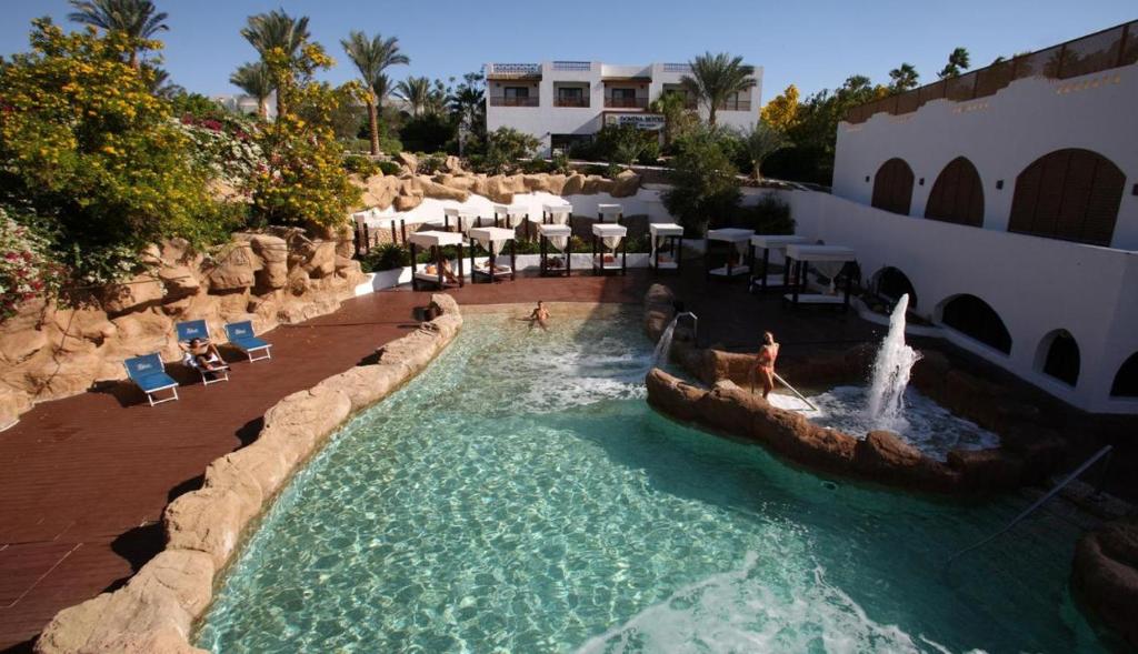 ein Pool in einem Resort mit Leuten, die darin spielen in der Unterkunft Suite esclusiva Domina Coral Bay Resort Spa & Casino in Sharm El Sheikh