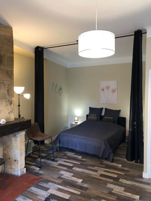 - une chambre avec un lit, une chaise et une cheminée dans l'établissement Escapade cosy au coeur de la cité médiévale, à Sarlat-la-Canéda