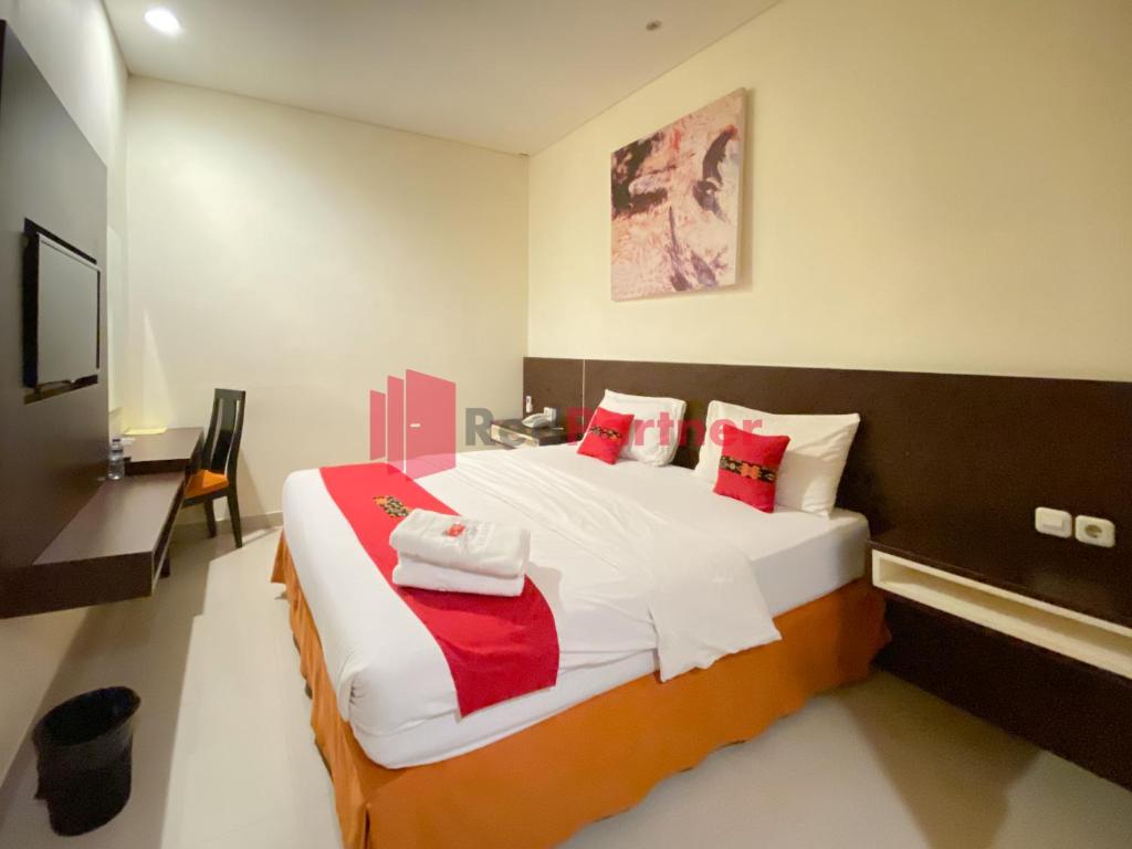 a bedroom with a large bed with red and white pillows at Hotel Alpha Makassar RedPartner in Makassar
