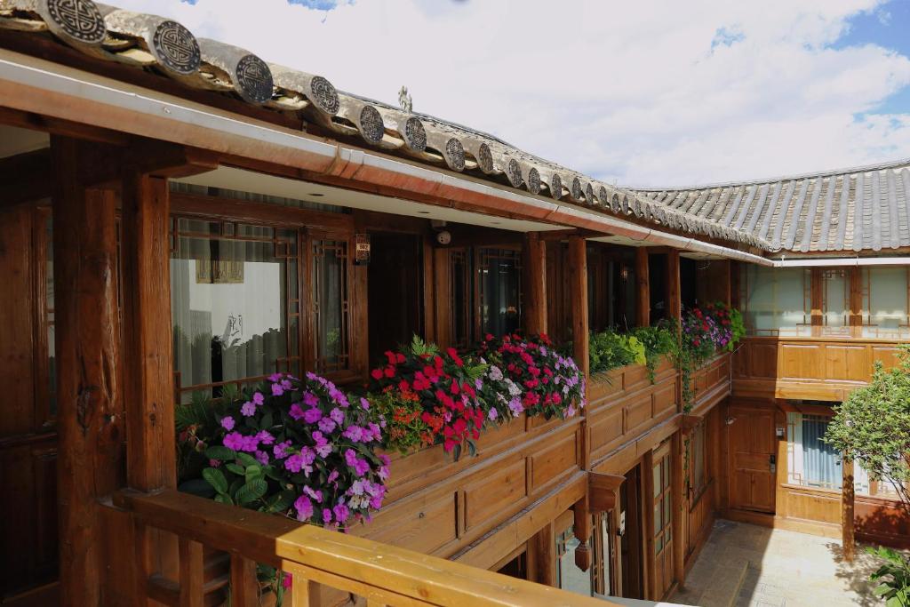 Un balcón de una casa con flores. en Saturday Inn en Lijiang
