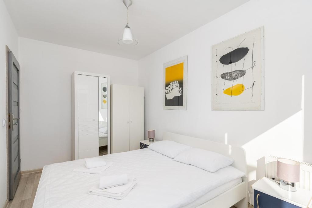 a white bedroom with a bed and a mirror at Borkowska Standard Apartment in Kraków