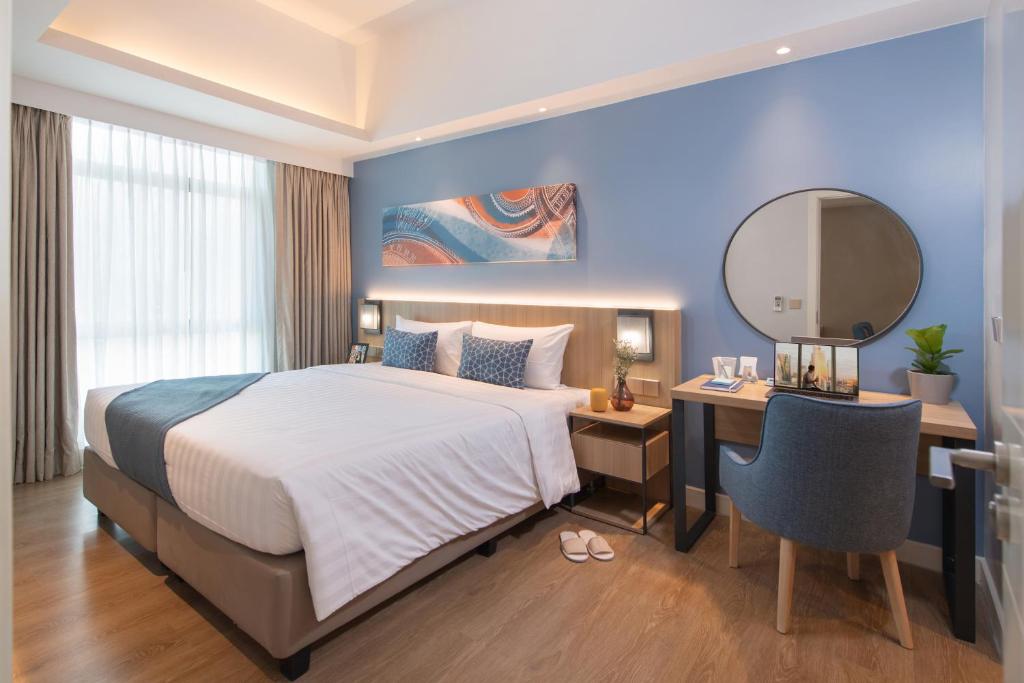 a bedroom with a bed and a desk and a mirror at Citadines Roces Quezon City in Manila