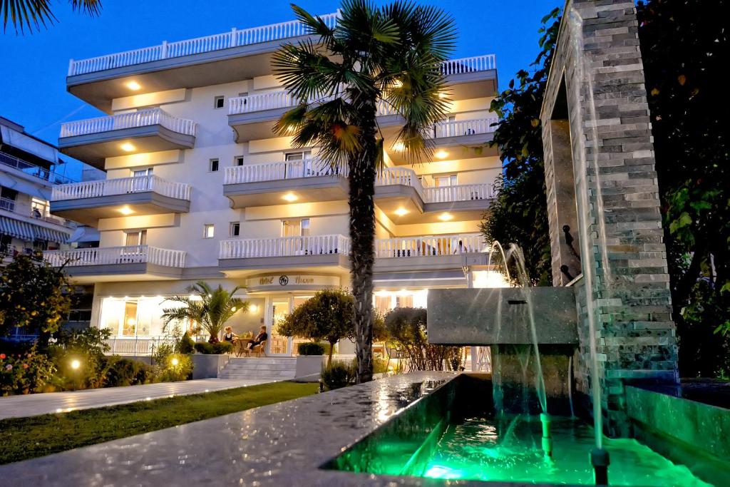 a hotel with a fountain in front of a building at Hotel Ioni in Paralia Katerinis