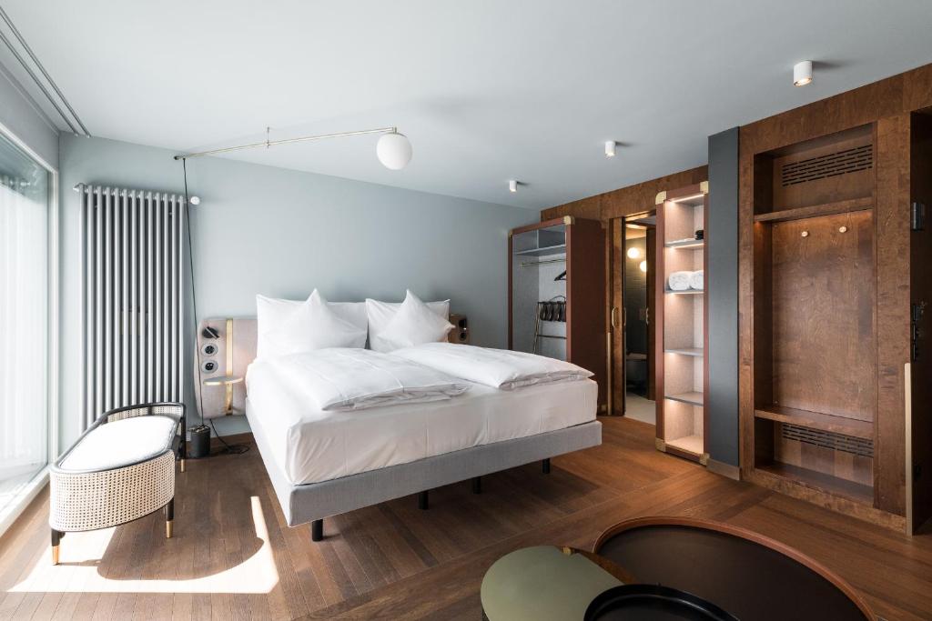 ein Schlafzimmer mit einem großen weißen Bett und einem Stuhl in der Unterkunft Hotel Aare Thun in Thun