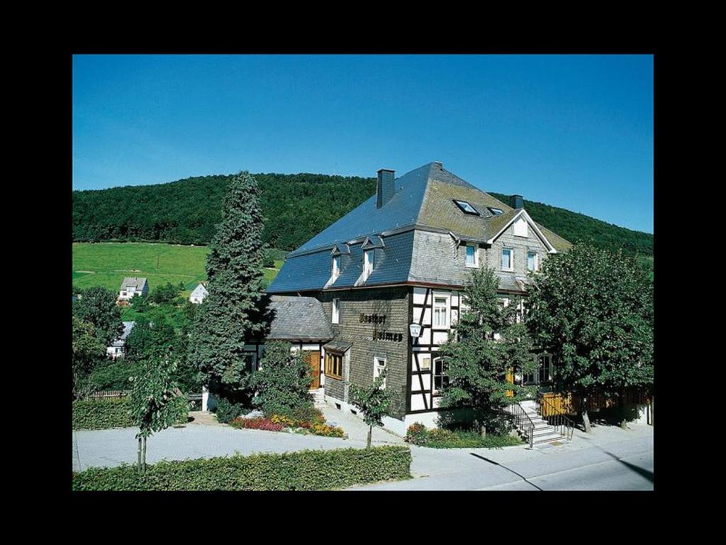 uma casa grande com um telhado preto numa colina em Gasthof Heimes em Schmallenberg