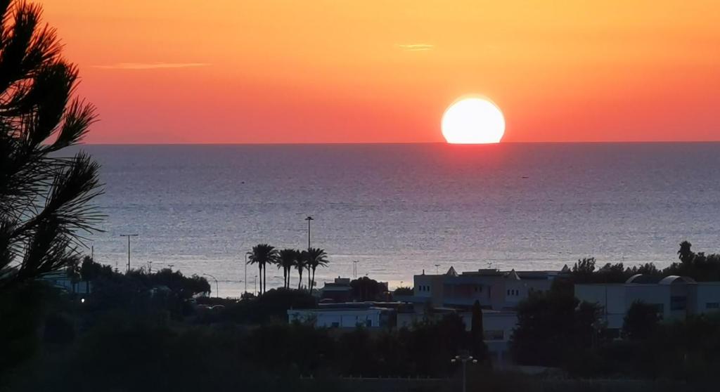 een zonsondergang over de oceaan met de zon in de horizon bij Residence IL CARRUBO in Gallipoli