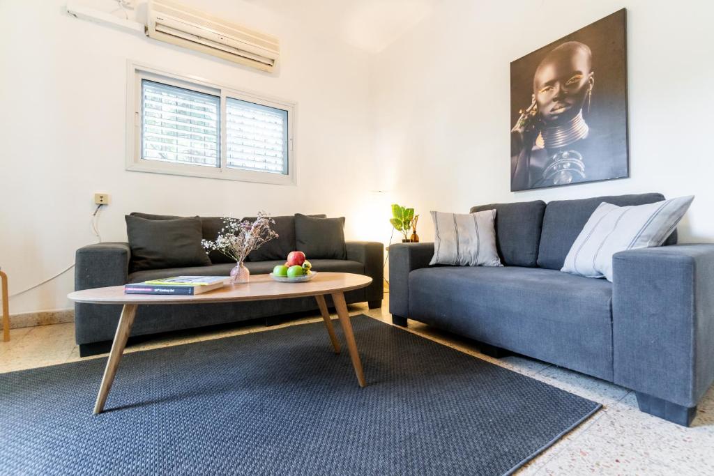 Ziv Apartments - Gottlieb 4 في تل أبيب: غرفة معيشة مع أريكة زرقاء وطاولة قهوة