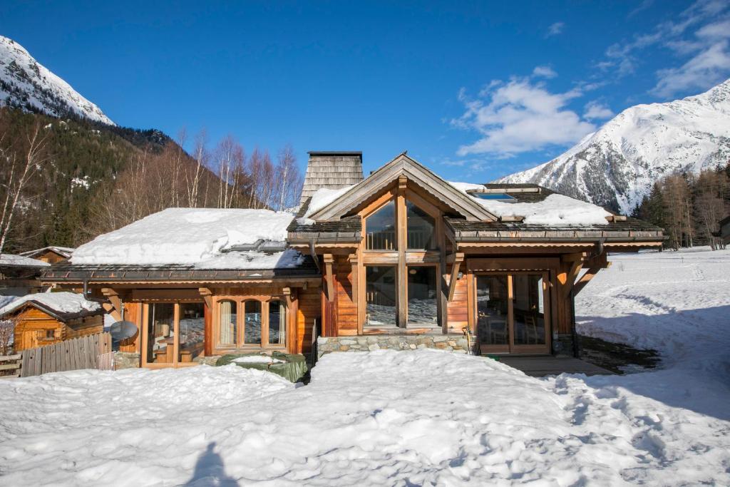 una baita di tronchi nella neve con le montagne di Chalets d'en haut - Bonheur - Happy Rentals a Chamonix-Mont-Blanc