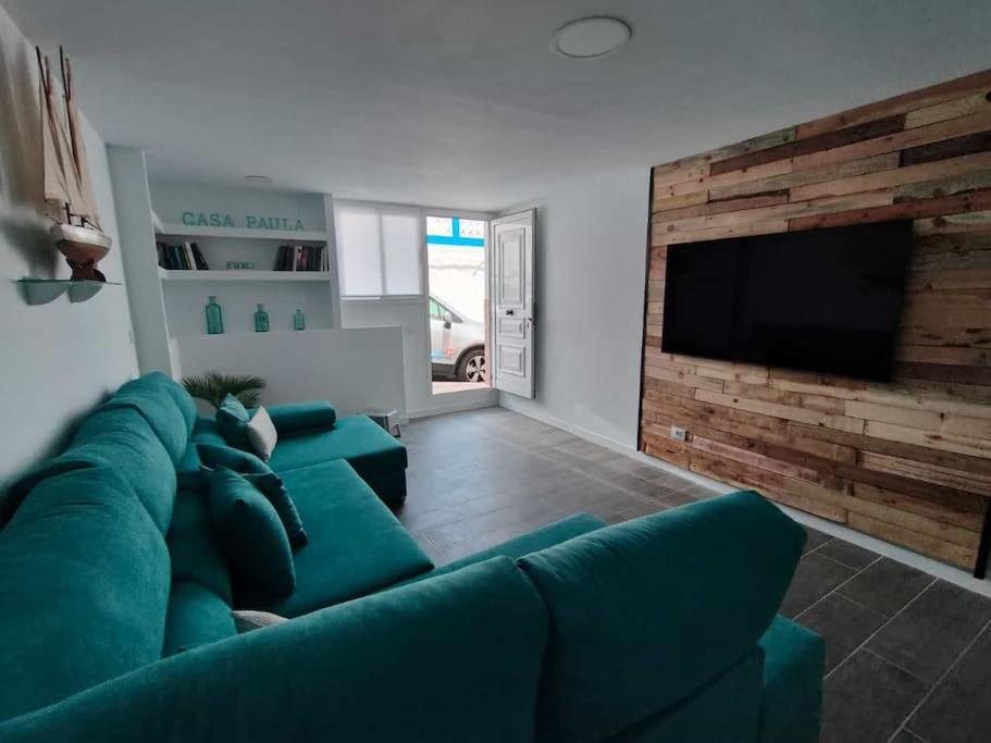 a living room with a green couch and a flat screen tv at Casa Paula in Las Playas