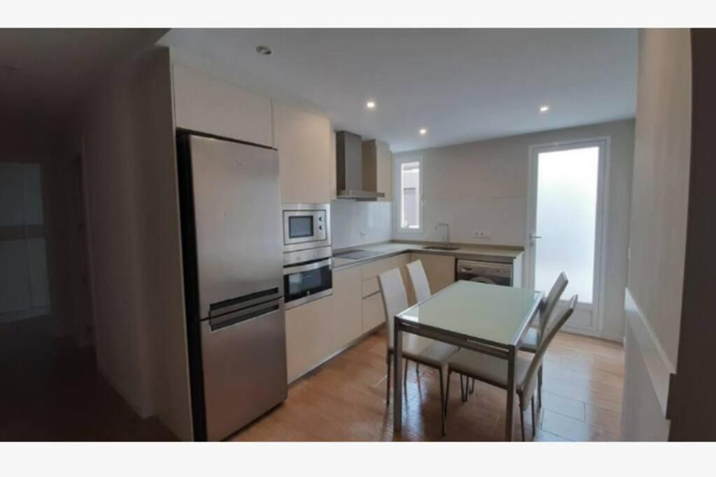 uma cozinha com uma mesa e um frigorífico de aço inoxidável em Apartamento céntrico de diseño en calle Tres Forques,Valencia em Valência