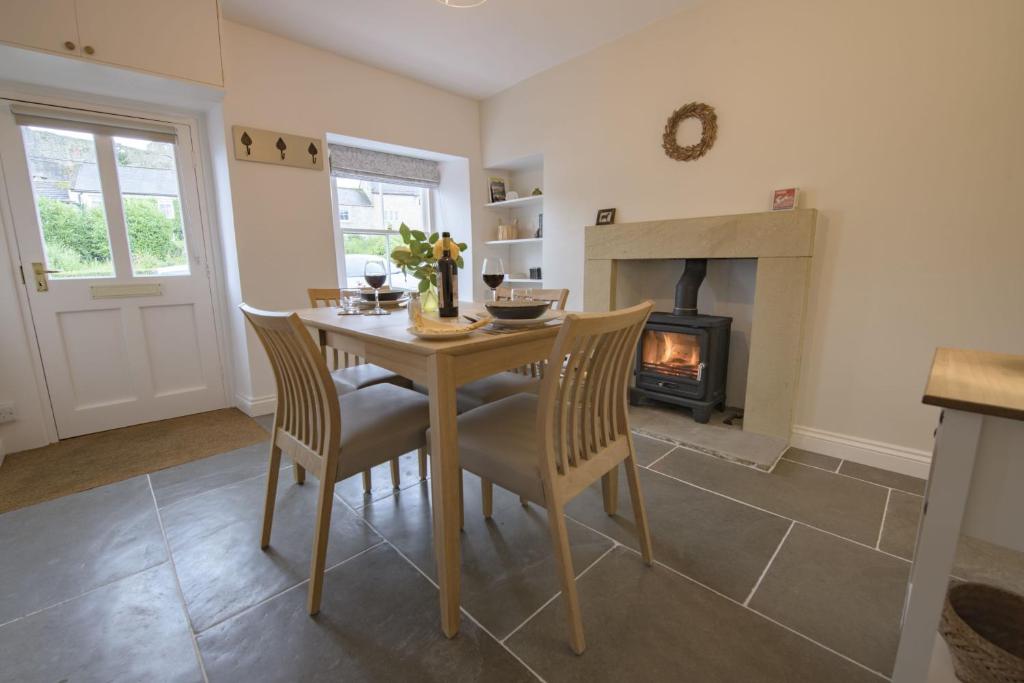 a dining room with a table and a fireplace at Penny Pot Cottage in Middleham