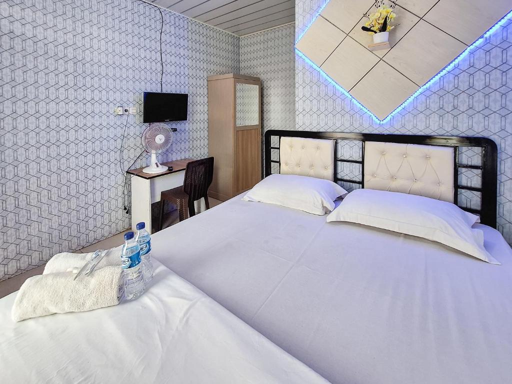 1 dormitorio con 1 cama blanca grande y escritorio en Homestay Sakinah Syariah Mitra RedDoorz, en Bukittinggi