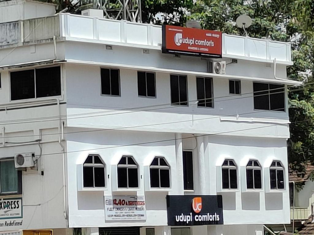 a white building with a sign on the side of it at Udupi Comforts in Udupi