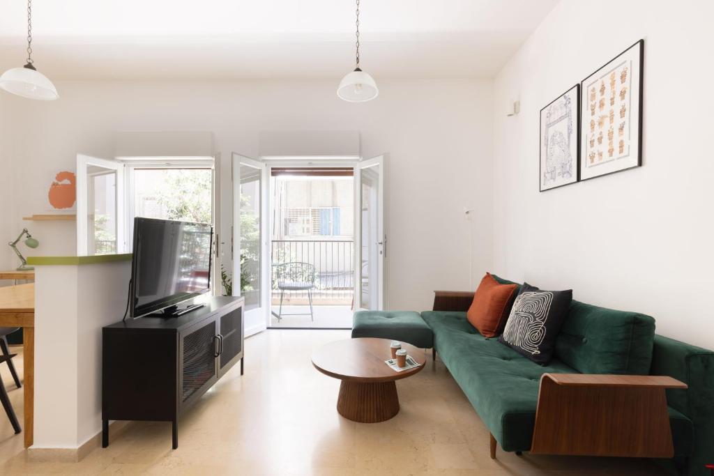 - un salon avec un canapé vert et une télévision dans l'établissement TLV2RENT Unique Dizengof Apartment, à Tel Aviv