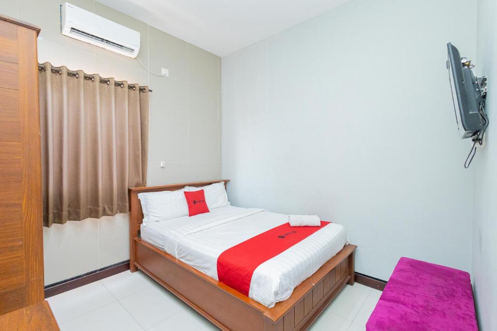 een kleine slaapkamer met een bed en een televisie bij OYO 90889 Dkb Residence in Surabaya