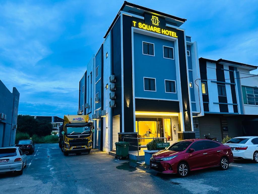 un bâtiment avec un camion et des voitures garés dans un parking dans l'établissement T SQUARE HOTEL (IPOH), à Ipoh