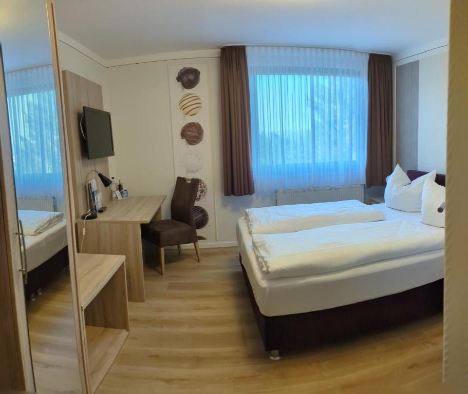 KirchbergにあるLandhotel Karrenbergのベッド2台と鏡が備わるホテルルームです。