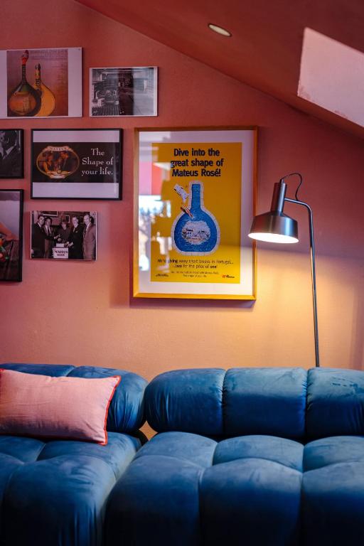 A blue velvet sofa in an art-filled lounge beneath a sloping ceiling.