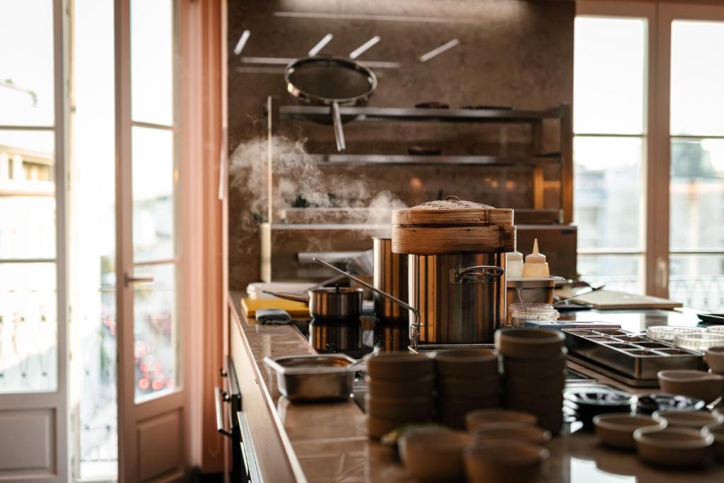 A close-up view of a steaming breakfast buffet beside tall windows.