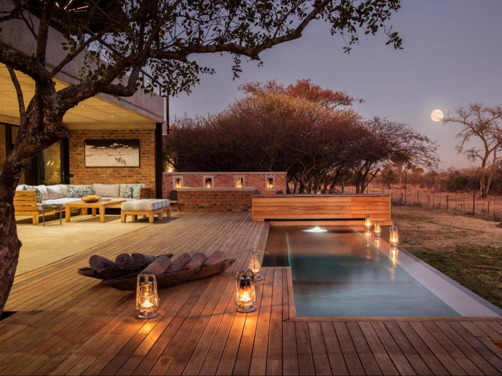 a backyard with a swimming pool and a wooden deck at NAKO Safari Lodge in Dinokeng Game Reserve