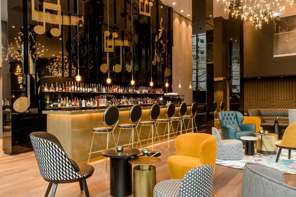 bar z żółtymi i niebieskimi krzesłami i blatem w obiekcie Motel One Warsaw-Chopin w Warszawie