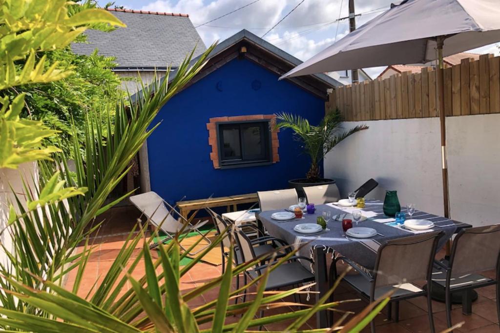 une table avec des chaises et un parasol sur une terrasse dans l'établissement Charming House In Pornichet Near The Beach, à Pornichet