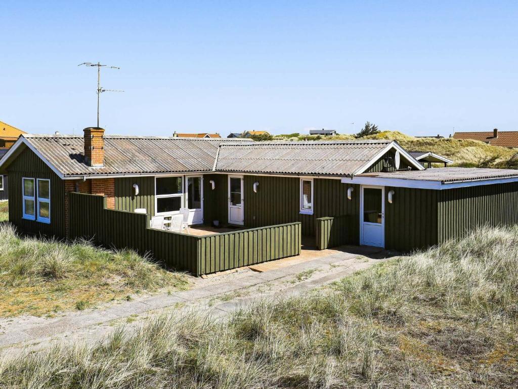 una casa verde al lado de una playa en 6 person holiday home in Ringk bing, en Søndervig