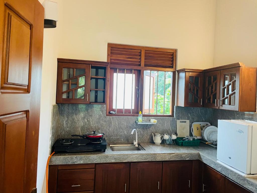 a kitchen with wooden cabinets and a sink at Royal Resort in Weligama
