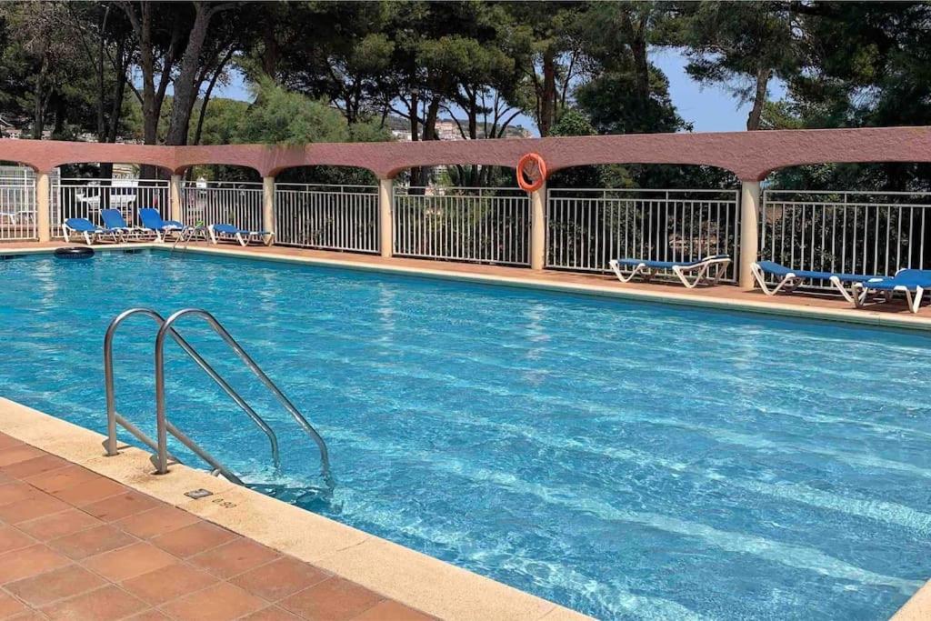 a large swimming pool with chairs at Apartament a L’Estartit x 4 in Torroella de Montgrí