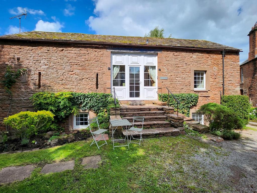 a brick house with a table and chairs in front of it at Highcroft & Windale @ Wetheral Cottages in Great Salkeld