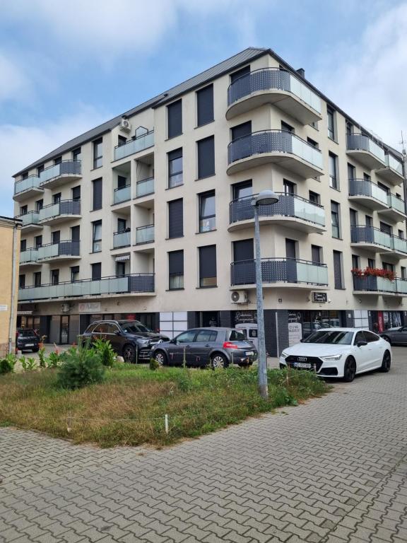 un grand bâtiment avec des voitures garées devant lui dans l'établissement Apartament Sky, à Leszno