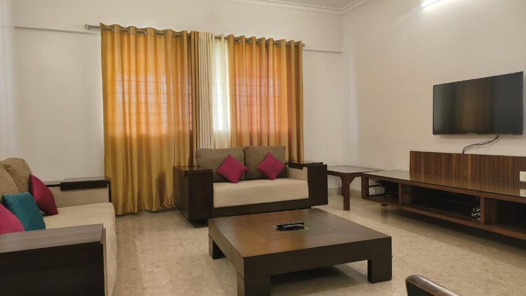 a living room with a couch and a flat screen tv at Just Homes - PG in Pune