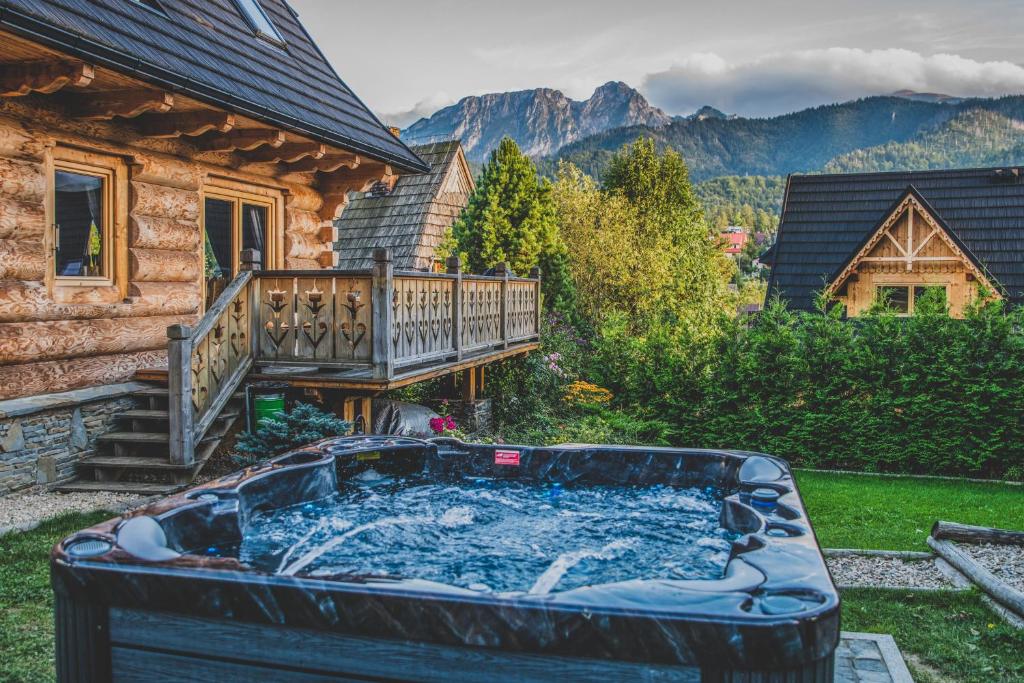 a hot tub in a yard next to a house at TatryTop Osada Luxury Chalets Kościelisko in Kościelisko