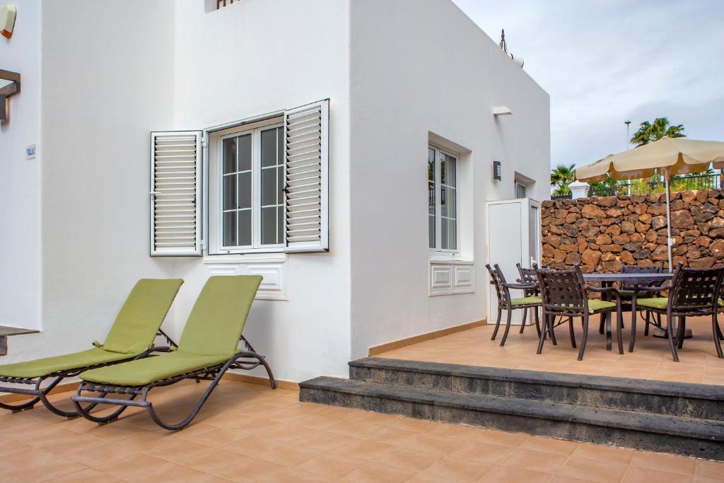 a patio with chairs and a table and a fence at Jardines del Sol in Playa Blanca