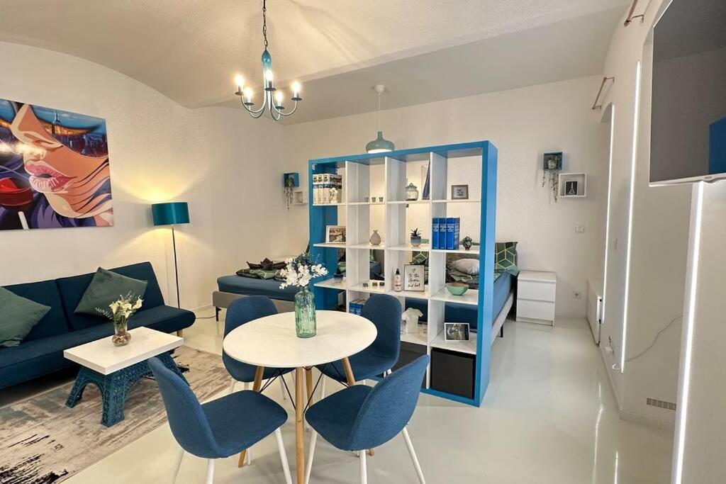 sala de estar con sofá azul, mesa y sillas en C’est la vie à Paris Apartment, en Viena