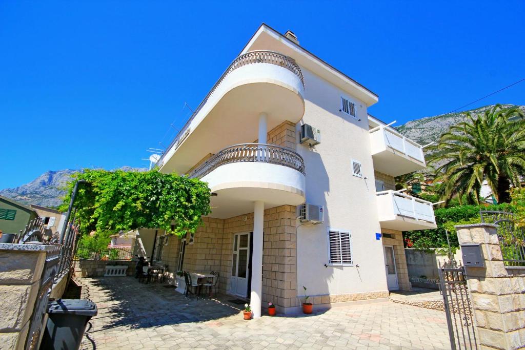 una gran casa blanca con un árbol delante en Apartment Makarska M&I, en Makarska