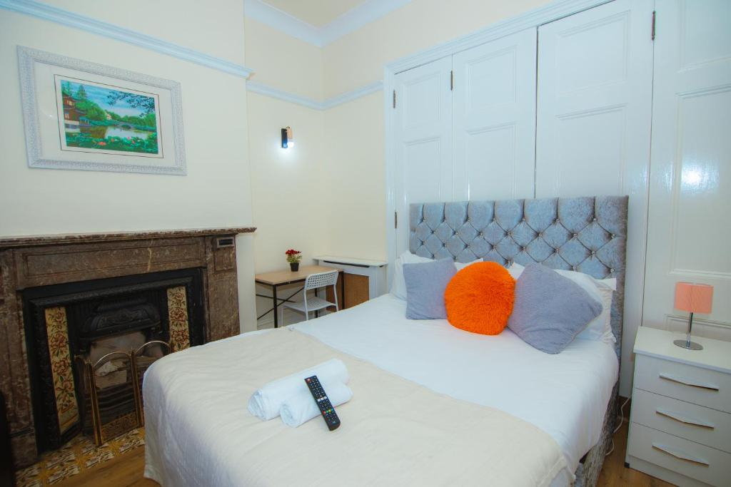 um quarto com uma cama branca com almofadas laranja e azul em Victorian Woods BnB em Londres