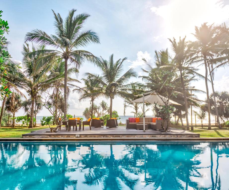 uma piscina no resort com palmeiras ao fundo em Sangria Sun em Wadduwa