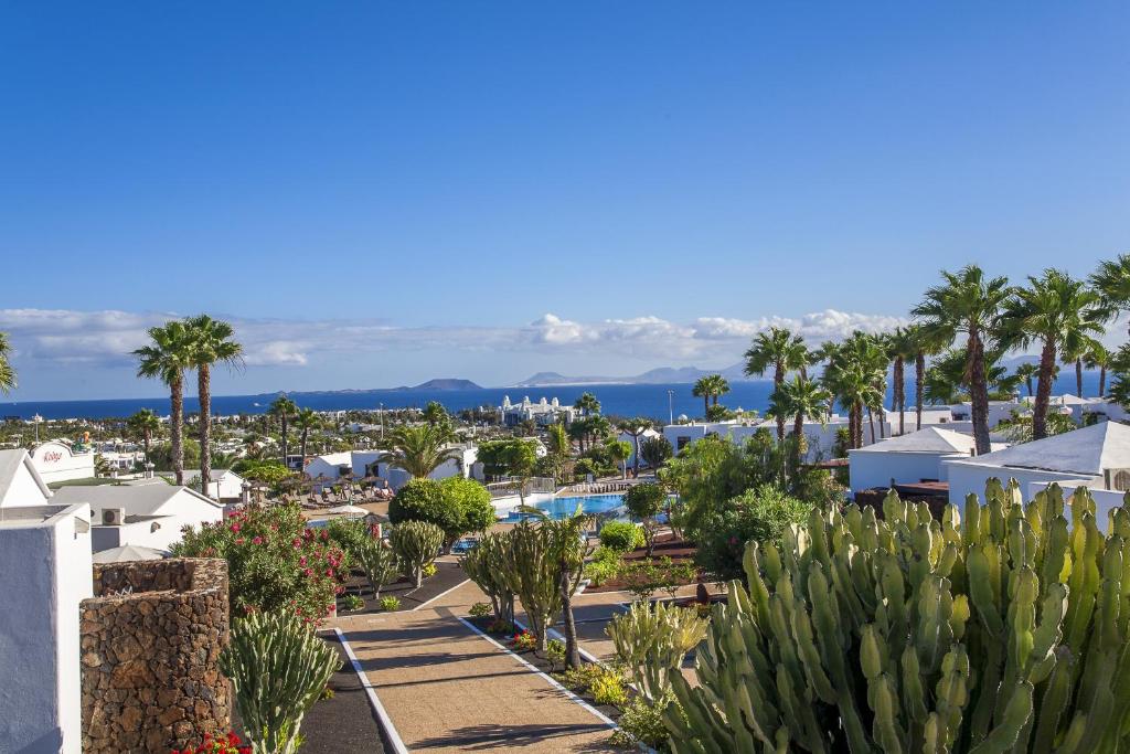 a view of a resort with palm trees and a pool at Jardines del Sol in Playa Blanca