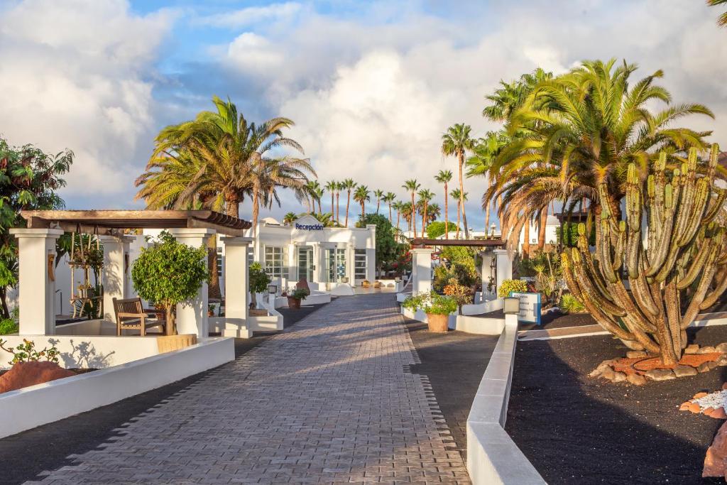 a resort with palm trees and a cobblestone street at Jardines del Sol in Playa Blanca