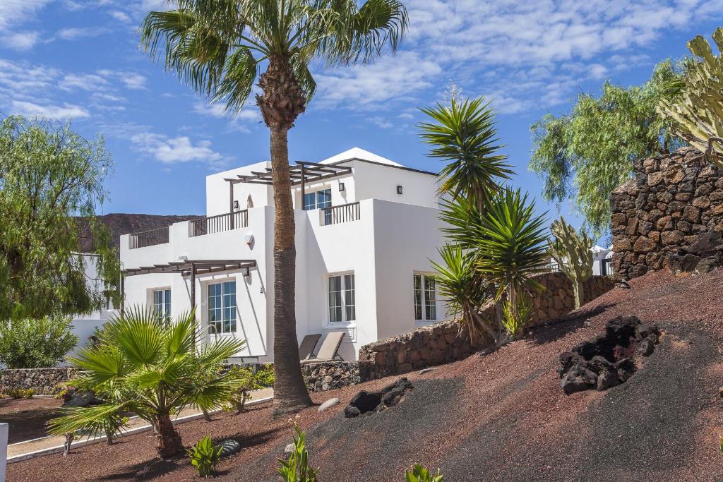 a white house with palm trees in front of it at Jardines del Sol in Playa Blanca