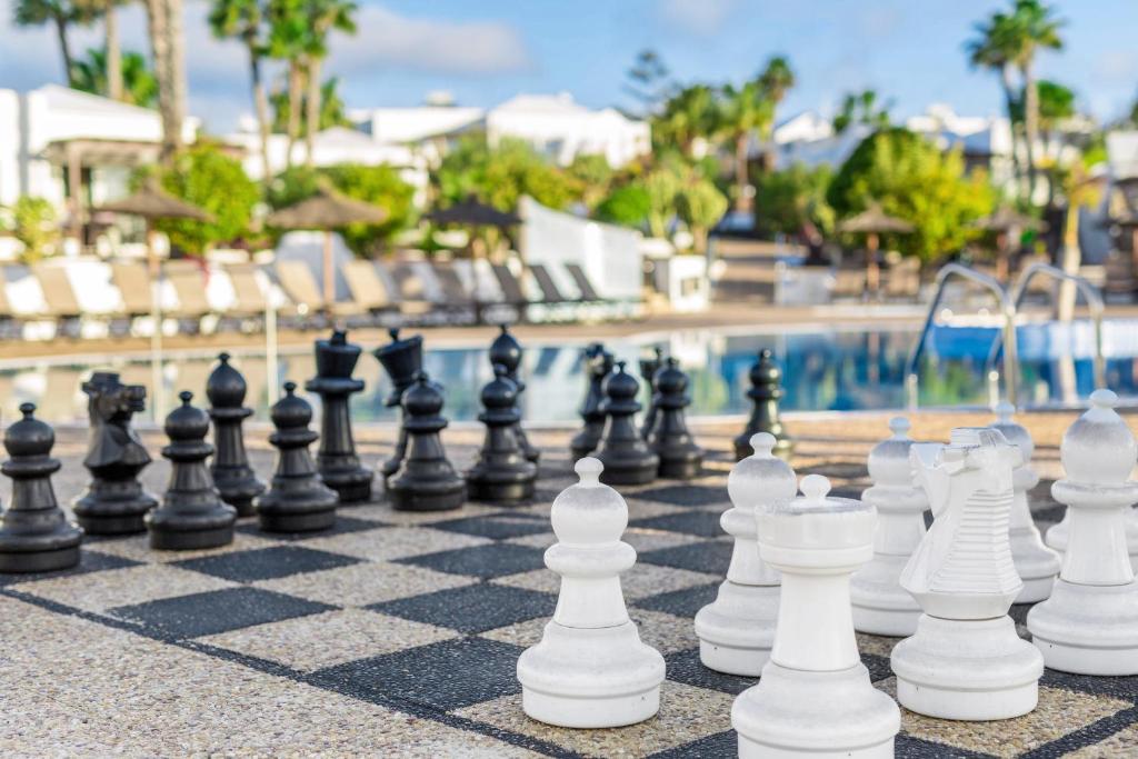 a chess board in front of a swimming pool at Jardines del Sol in Playa Blanca