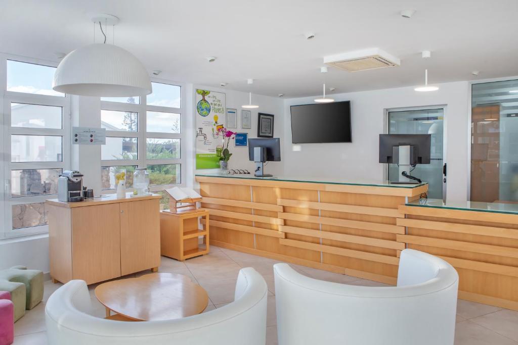a waiting room with white chairs and a counter at Jardines del Sol in Playa Blanca