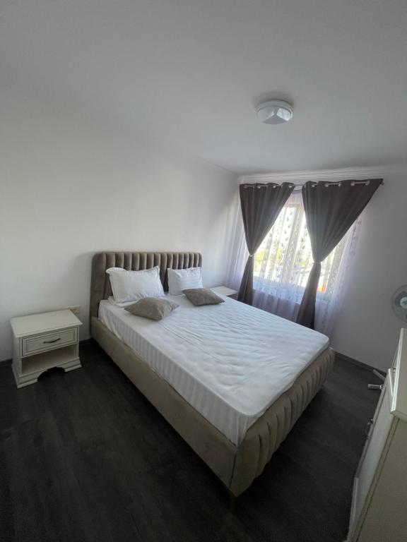 una camera da letto con un letto con lenzuola bianche e una finestra di Sara’S Apartament a Suceava