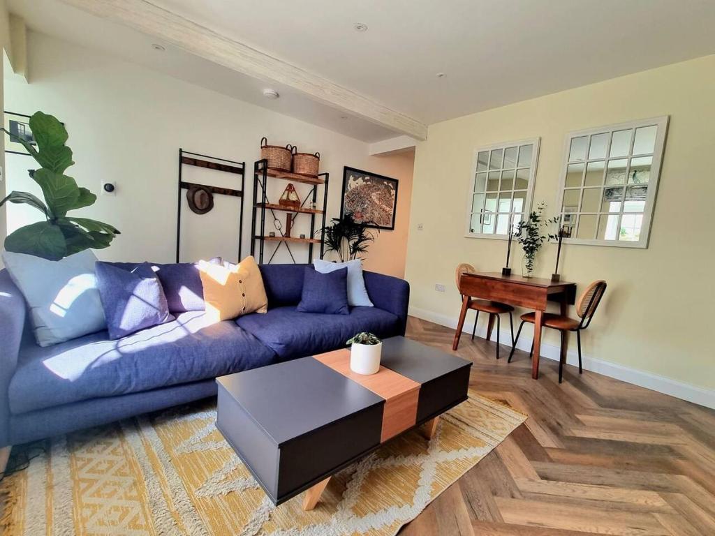 een woonkamer met een blauwe bank en een tafel bij Spacious & Renovated 1-Bed Garden Flat in London in Londen